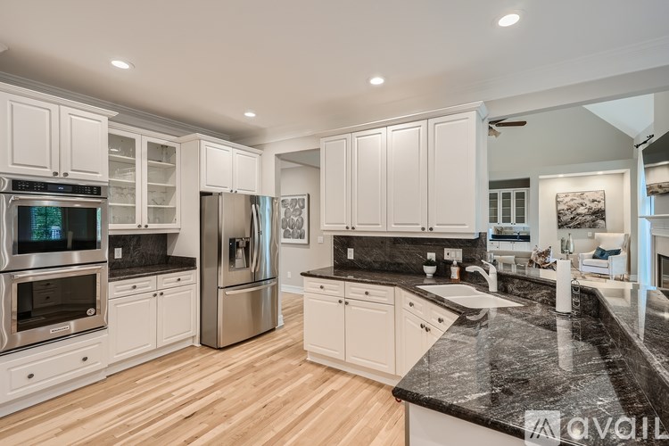 A modern kitchen with white cabinets and black countertops.