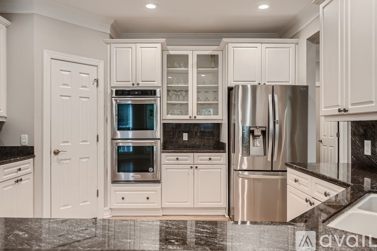 A kitchen with white cabinets and a black countertop.