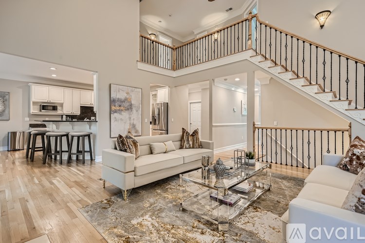 A living room with a staircase and a glass coffee table.
