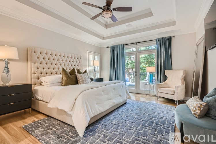 A bedroom with a large bed, a ceiling fan, and a chair.