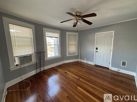 A room with a ceiling fan and wooden flooring.