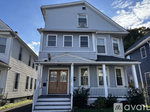 A two-story house with a front porch and a brown door.