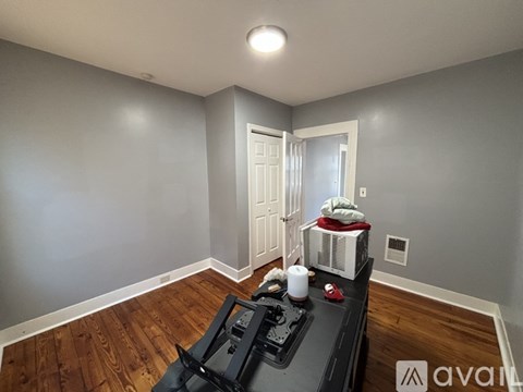 A room with a black stove top oven and wooden flooring.