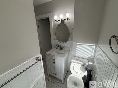 A bathroom with a toilet, sink, and mirror.