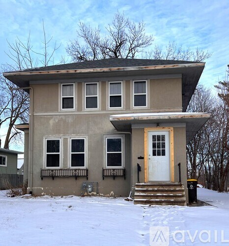 A house with a white door and windows is surrounded by snow.