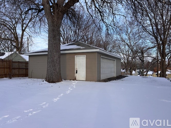 A house with a garage and a tree in front of it.
