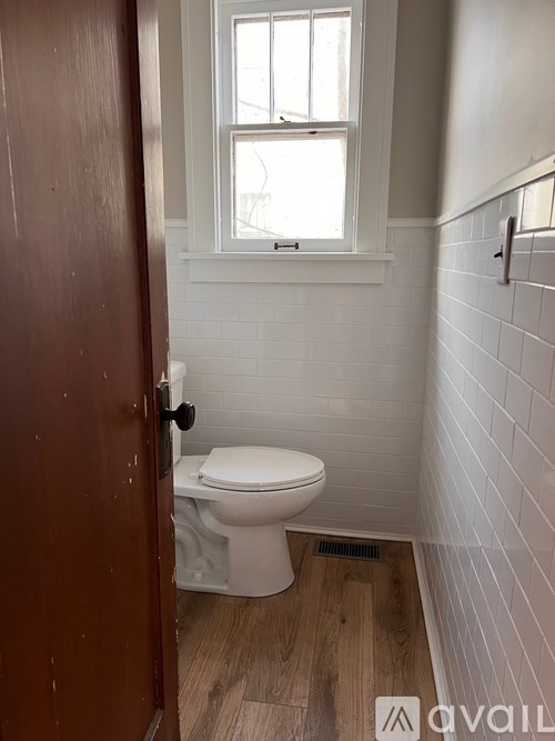 A white toilet in a small bathroom with a wooden door.
