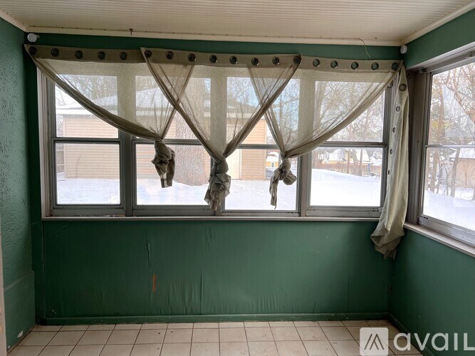 A room with green walls and a window with curtains.