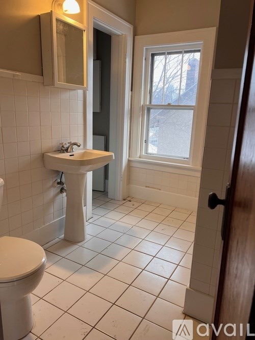 A bathroom with a toilet, sink, and a window.