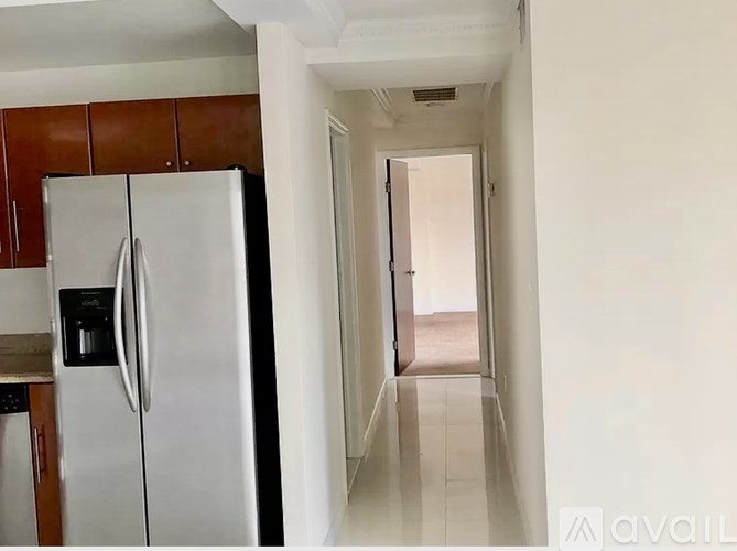 A white refrigerator is in a kitchen with brown cabinets.