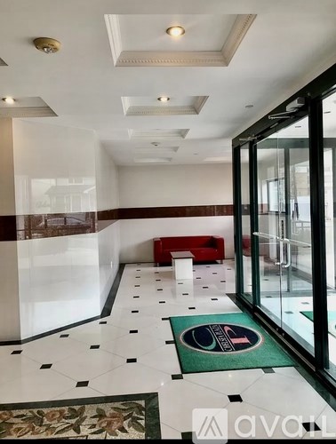 A hallway with a red bench and a green mat with a logo on it.