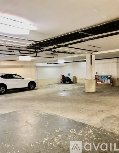 A white car is parked in a garage with a dog sitting on the floor.