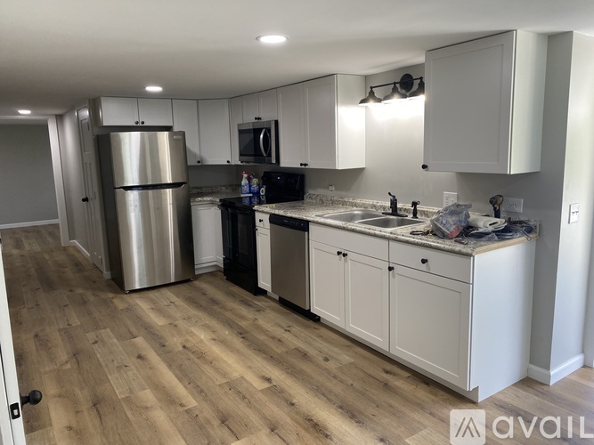 A kitchen with white cabinets and a wooden floor.