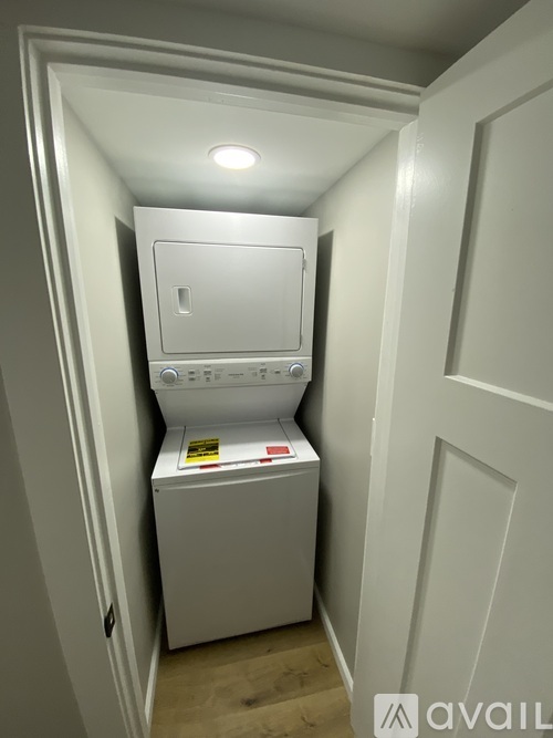 A small white washing machine sits in a narrow space between two walls.