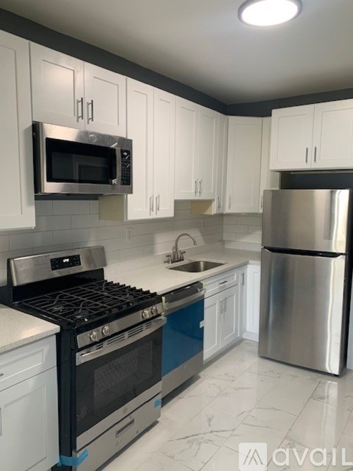 A kitchen with white cabinets and a stainless steel refrigerator.