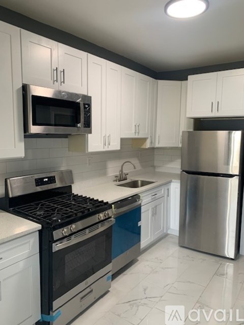 A kitchen with white cabinets and a stainless steel refrigerator.