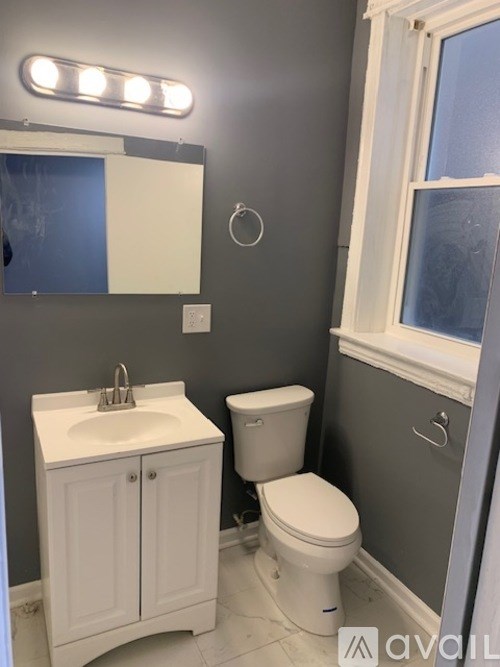A bathroom with a toilet, sink, and mirror.