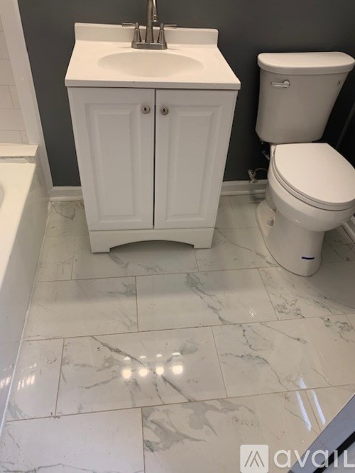 A white cabinet with a sink is in a bathroom with a toilet.