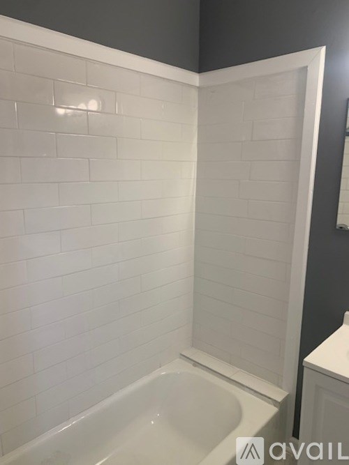 A white tiled bathroom with a white tub and a white toilet.