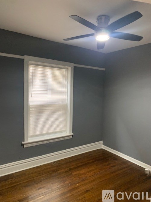 A room with a ceiling fan and a window with blinds.