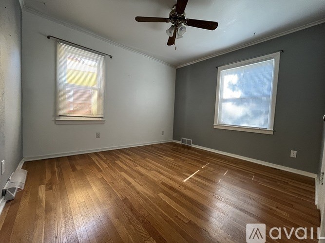 A room with a ceiling fan and two windows.