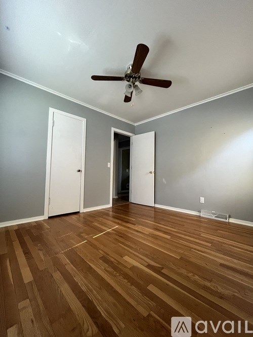 A room with a ceiling fan and wooden flooring.