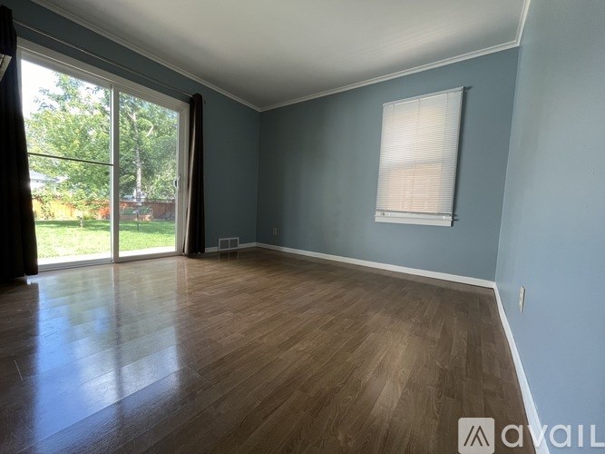 A room with wooden flooring and a window with blinds.