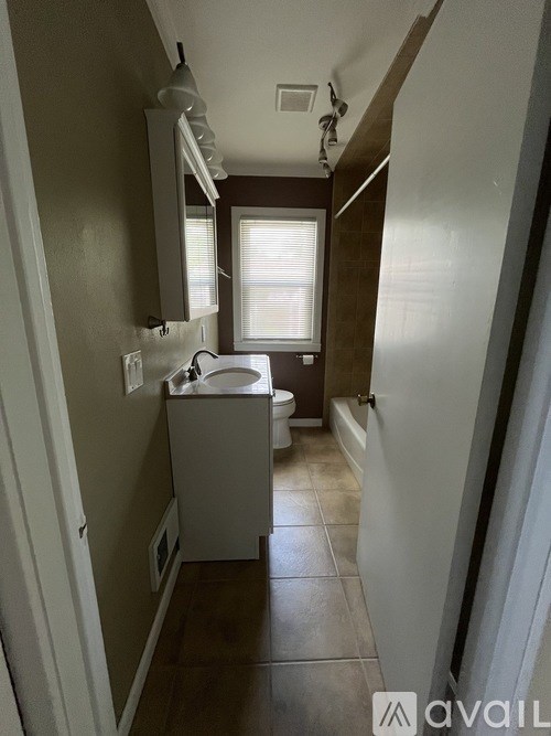 A bathroom with a toilet, sink, and mirror.