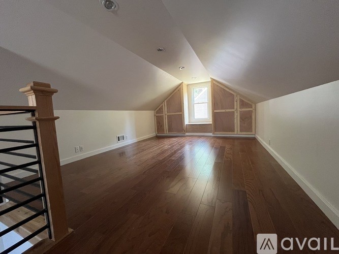 A room with wooden floors and a window in the far wall.