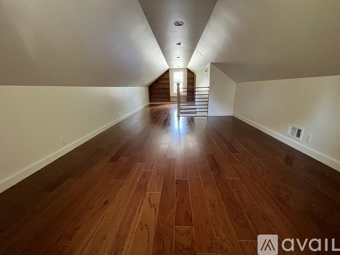 A long hallway with wooden floors and a staircase in the distance.
