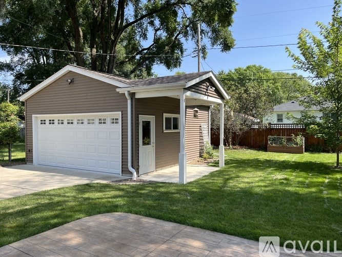 A two-car garage with a brown roof and a white door is situated in a grassy area.