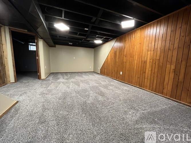 A room with a carpeted floor and wooden walls.