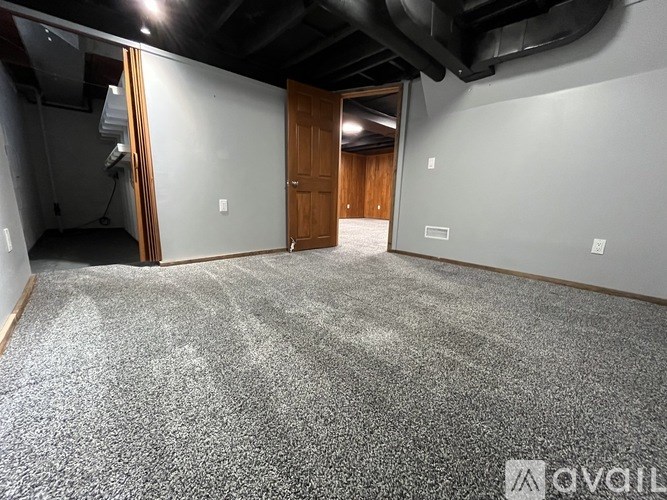 A room with a grey carpet and a wooden door.