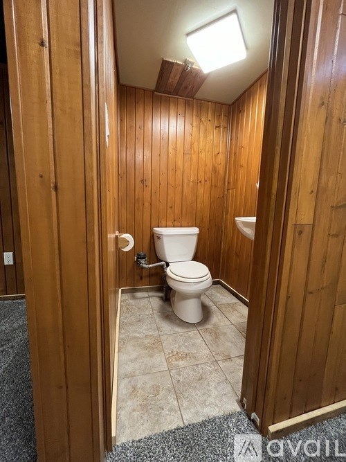 A small bathroom with a toilet and wooden walls.