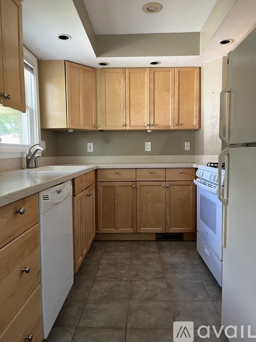 A kitchen with wooden cabinets and a white dishwasher.
