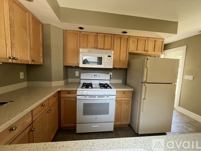 A kitchen with wooden cabinets and a white stove top oven.