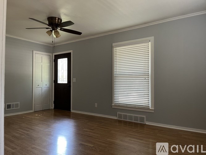 A room with a ceiling fan and a window with blinds.