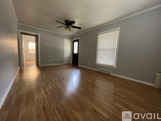 A spacious room with wooden flooring and a ceiling fan.