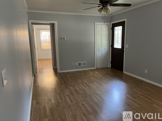 A room with a ceiling fan and wooden flooring.