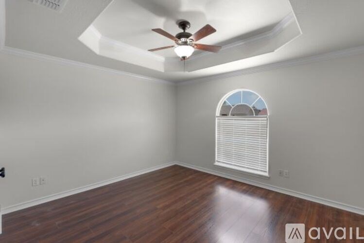 A room with a ceiling fan and a window with blinds.