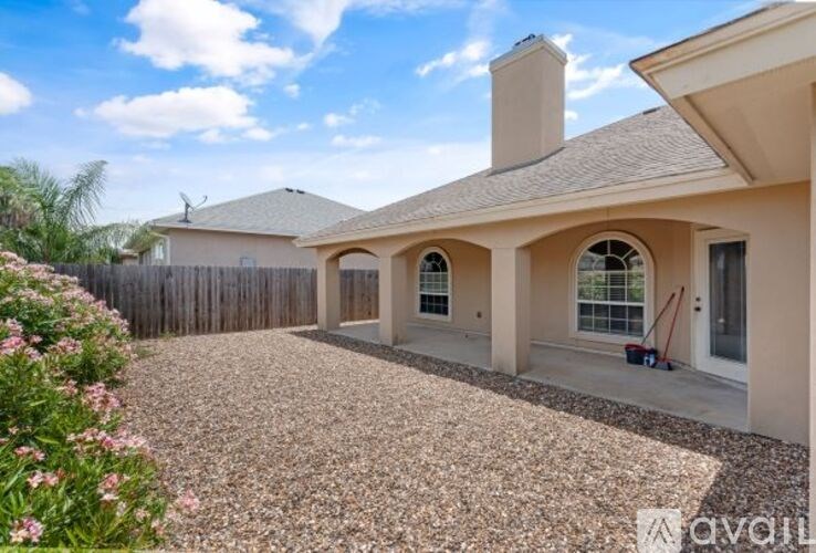 A house with a gravel driveway and a fence in the background.