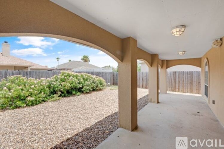 A patio area with a gravel ground and a wooden fence.