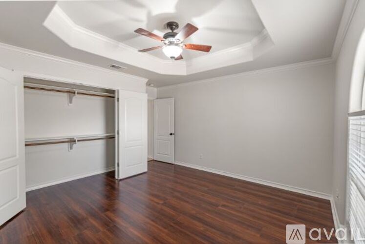 A room with a ceiling fan and wooden flooring.