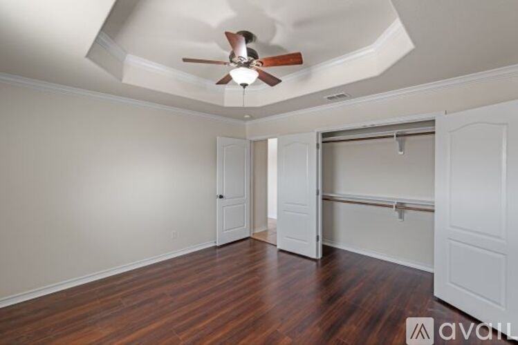A room with a ceiling fan and wooden floors.