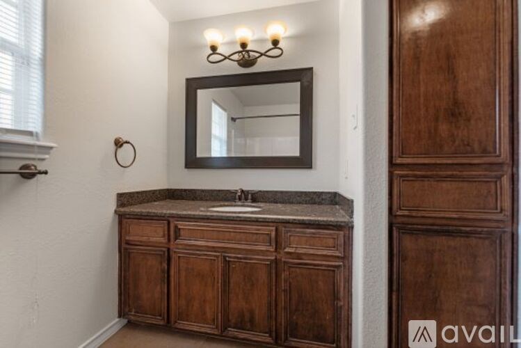 A bathroom with a wooden vanity and a mirror above it.
