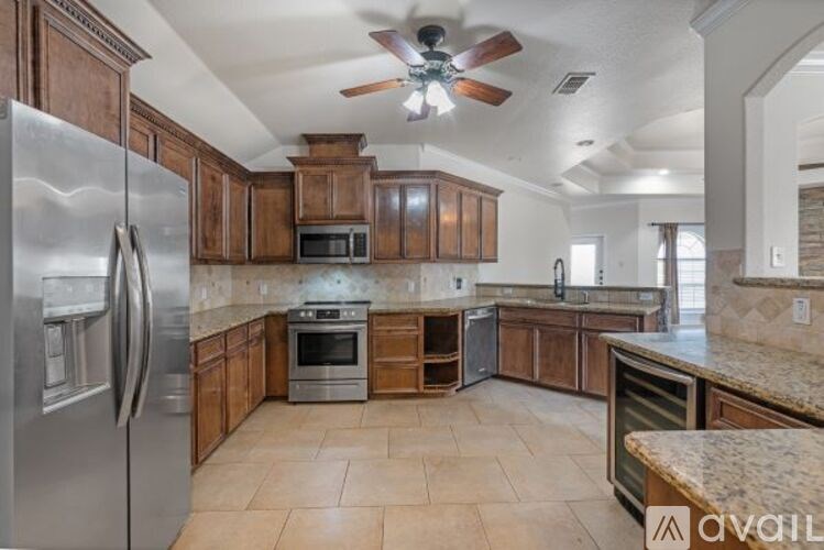 A kitchen with a refrigerator, microwave, oven, and cabinets.