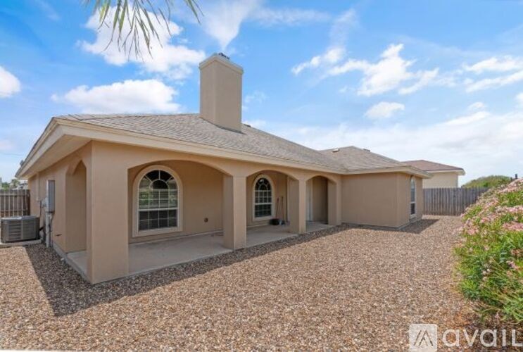 A house with a gravel driveway and a palm tree in the background.
