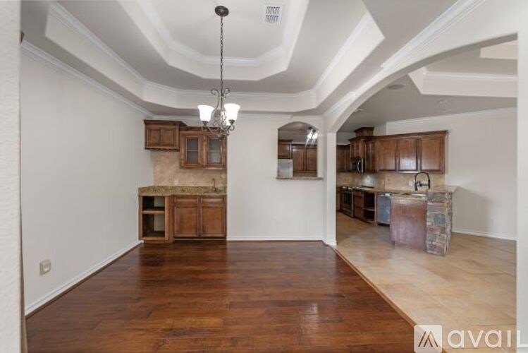 A room with wooden floors and a chandelier hanging from the ceiling.