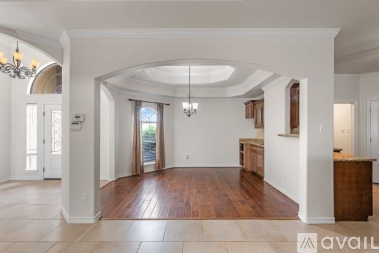 A spacious room with a wooden floor and a chandelier hanging from the ceiling.