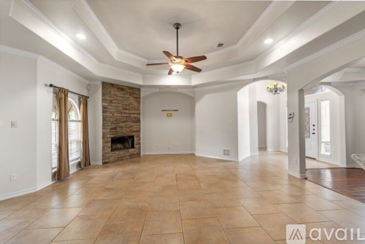 A spacious living room with a fireplace and a fan on the ceiling.